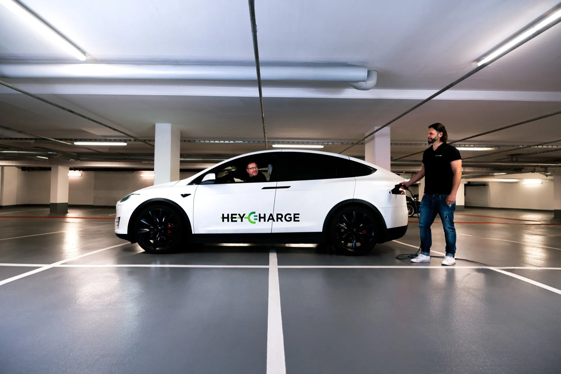 HeyCharge founders plugging in a Tesla at a HeyCharge-equipped garage